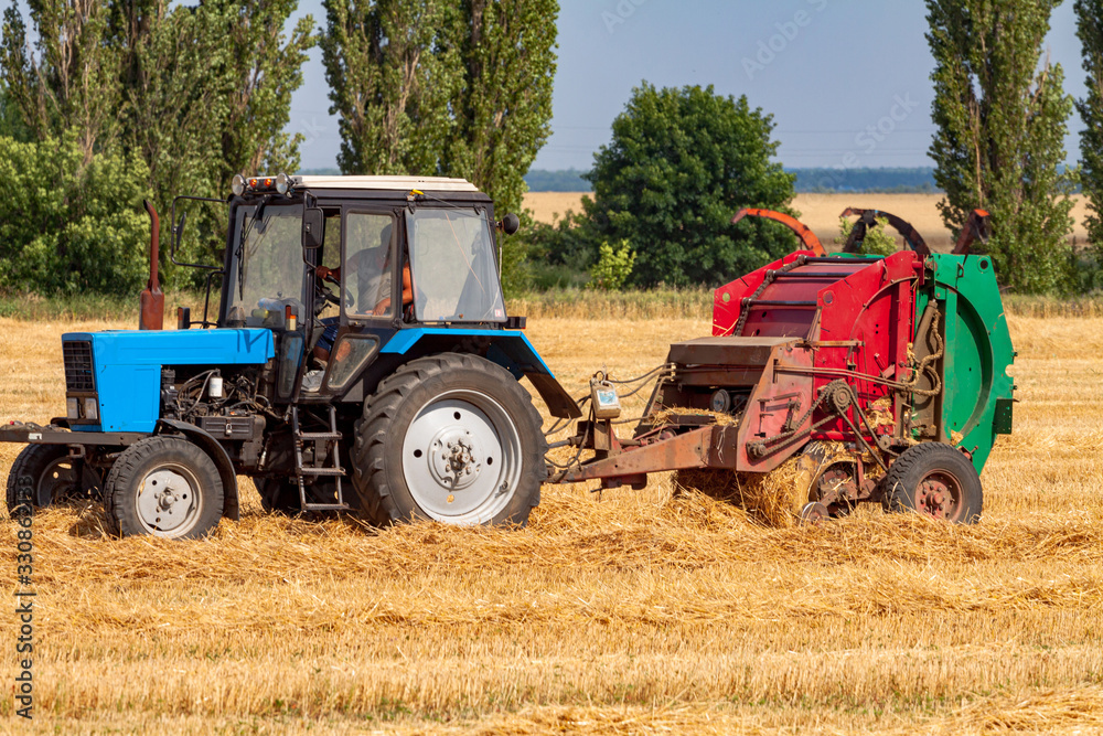 tractor makes big straw roll on yellow field at summer day tractor makes big straw roll on yellow field at summer day
