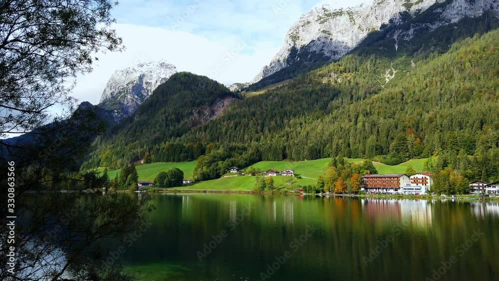 Idyllic panorama view of Hintersee lake with beautiful reflections of trees and house and Bavarian Alps and blue sky cloud in background, near Konigssee lake, Ramsau in Berchtesgaden, Bavaria, Germany Idyllic panorama view of Hintersee lake with beautiful reflections of trees and house and Bavarian Alps and blue sky cloud in background, near Konigssee lake, Ramsau in Berchtesgaden, Bavaria, Germany