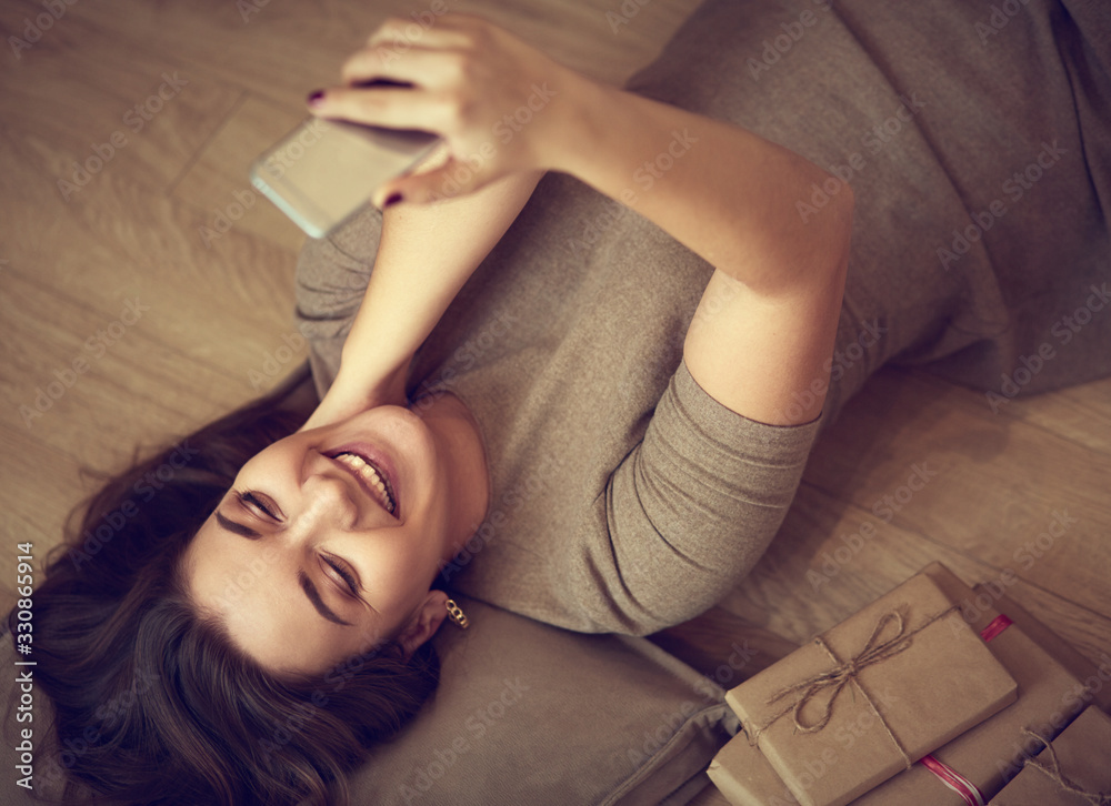 Obraz premium Top view of a woman using her phone while lying on her back