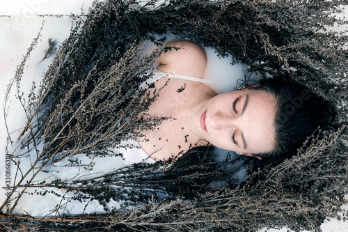 Fotografie Herbalist girl lies in a bathtub with wormwood