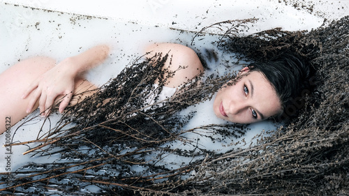 Fotografie Herbalist girl lies in a bathtub with wormwood