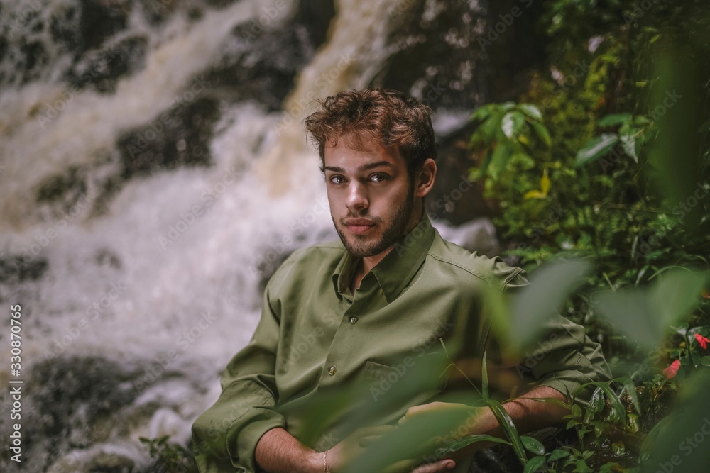 young man in the forest with waterfall background 