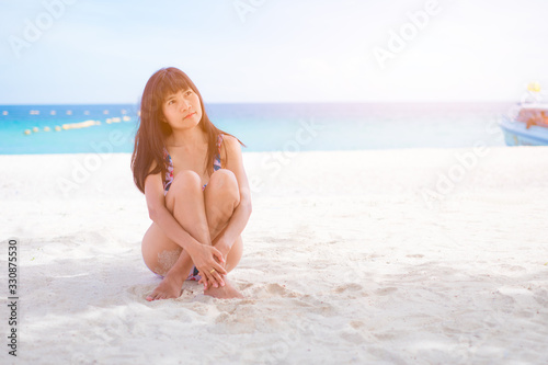 Asian women siting on sea beach with swimming suit she happy of outdoor summer on sand beach with blue sky and sea, well editing text present for your project with tourism and travel on summer season © wing-wing