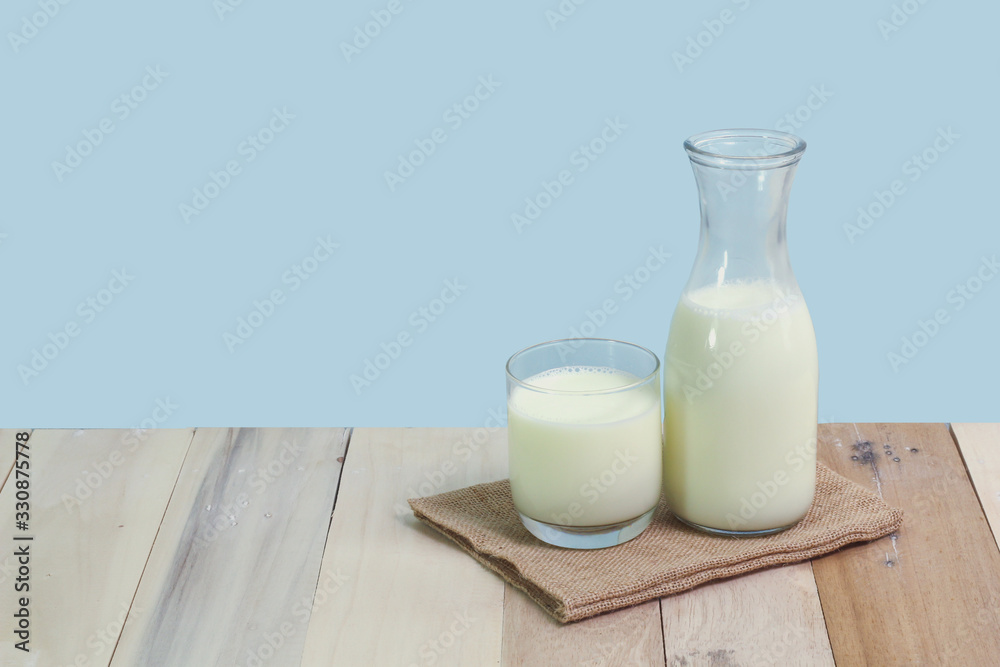 A bottle of rustic milk and glass of milk on a wooden table A bottle of rustic milk and glass of milk on a wooden table