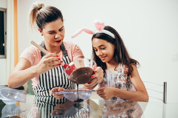 Mother and daughter making homemade chocolate easter eggs. Easter in Brazil.