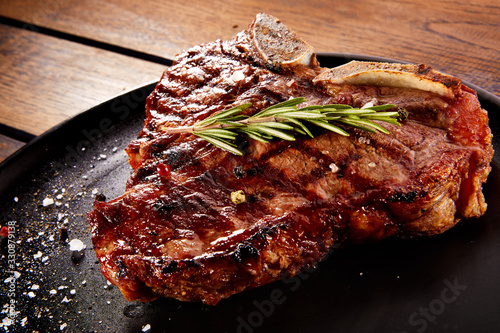 Fényképezés Grilled beef steak with rosemary, salt and pepper on black stone plate