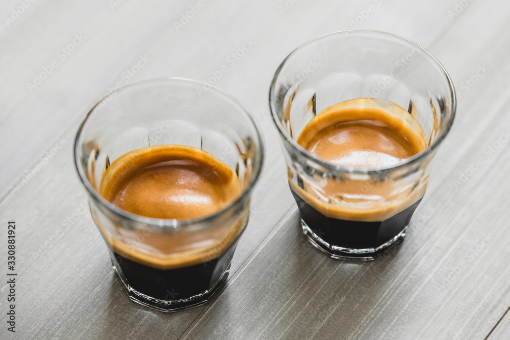 Double shot Espresso coffee in the glasses on vintage wood table background Double shot Espresso coffee in the glasses on vintage wood table background