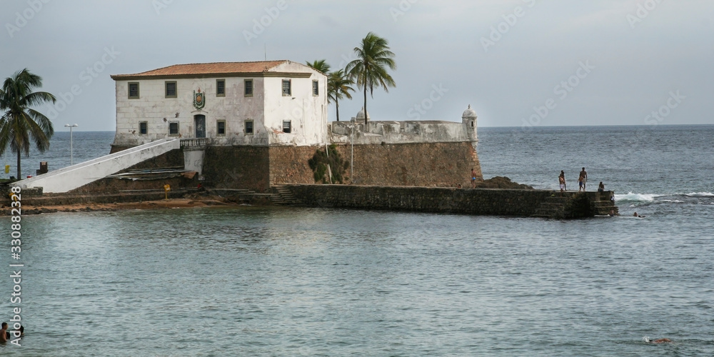 Forte na beira do mar em Salvador com banhistas pulando das pedras na água