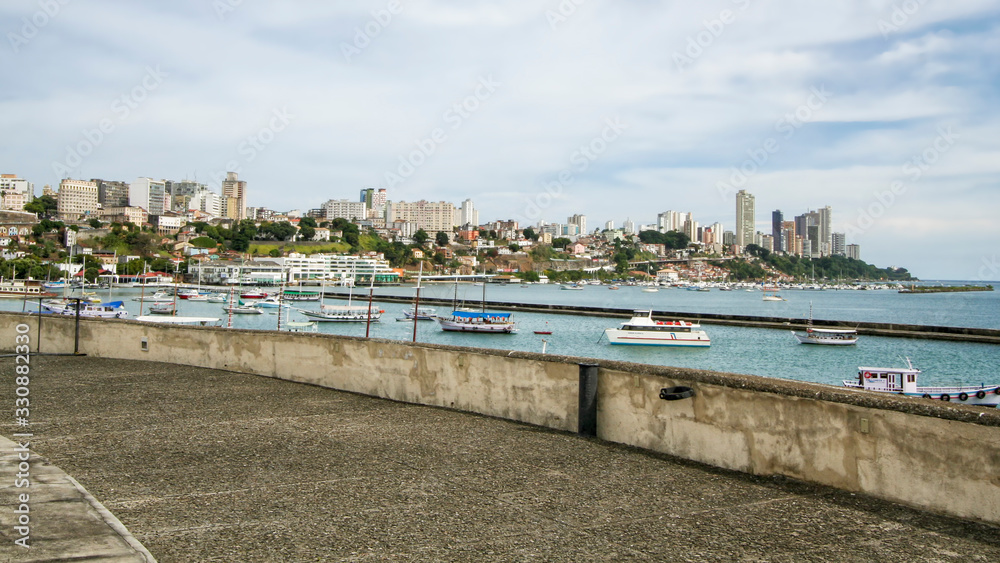 Forte e orla de Salvador, na Bahia, com barcos distantes coloridos ancorados