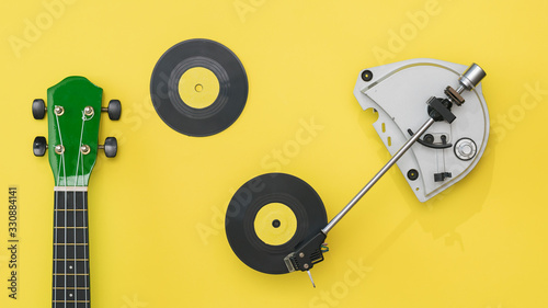 Ukulele guitar, vinyl record player and discs on a yellow background. photo