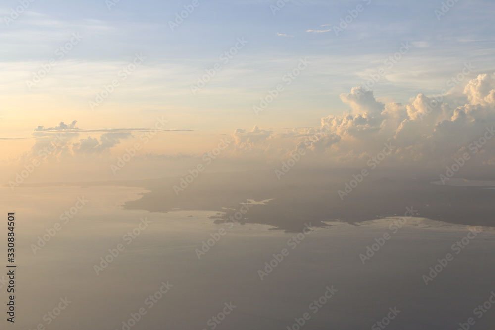 Dramatic cloudscape and landscape during sunrise from the airplane's window