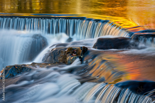Golden hues of autumn are reflected in the surface of the Ontonagon River at Upper Bond Falls, Bond Falls Scenic Site, Michigan.