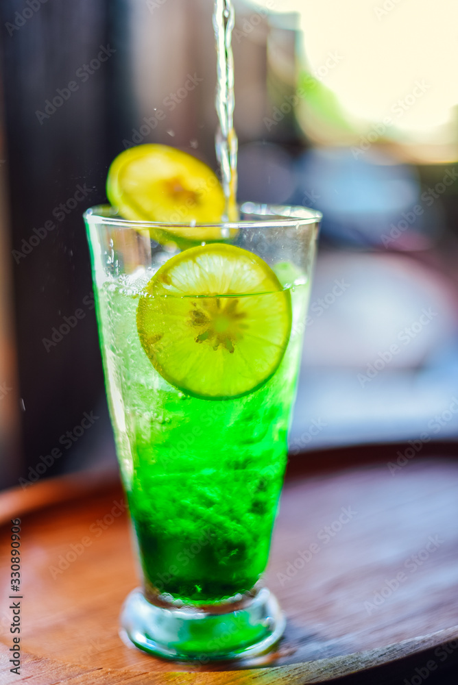 Iced green soda with lemon in glass on wood table. Iced green soda with lemon in glass on wood table.