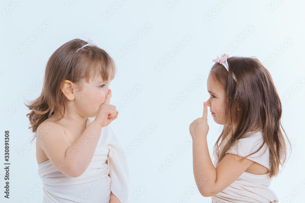 two little girls shake their fingers at a white background. Children raise each other. the concept of education , childhood, and Sisterhood. Copy space two little girls shake their fingers at a white background. Children raise each other. the concept of education , childhood, and Sisterhood. Copy space