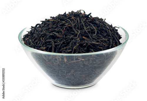 Black loose tea in a glass bowl, isolated on white background. Good quality Ceylon tea with big opa leaves.