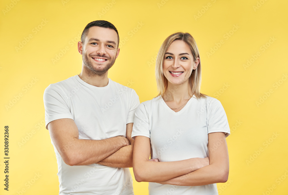Young happy couple with arms crossed over yellow background Young happy couple with arms crossed over yellow background