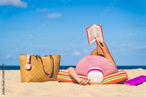 Women are sunbathing and read book on the beach there are bags and books on the side During the holidays in good weather and clear skies during summer, holidays and activities concept with copy space.
