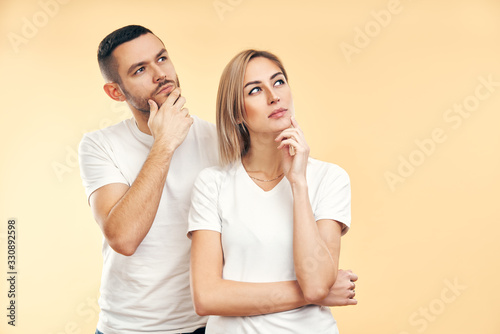 Young thoughtful man and woman looking sideways isolated on beige background
