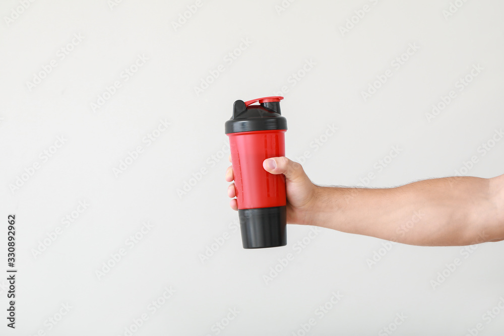 Naklejka premium Male hand with protein shake on light background