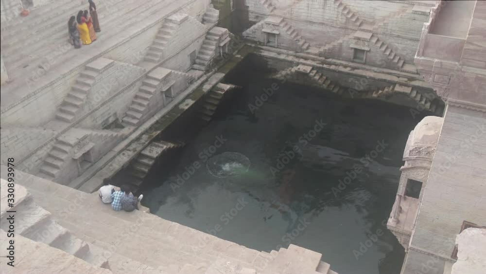 Three kids look as man in black shorts takes a dive into a beautiful step well in Jodhpur India known as Toorji Ka Jhalra or Toorji’s Step Well. Three kids look as man in black shorts takes a dive into a beautiful step well in Jodhpur India known as Toorji Ka Jhalra or Toorji’s Step Well.