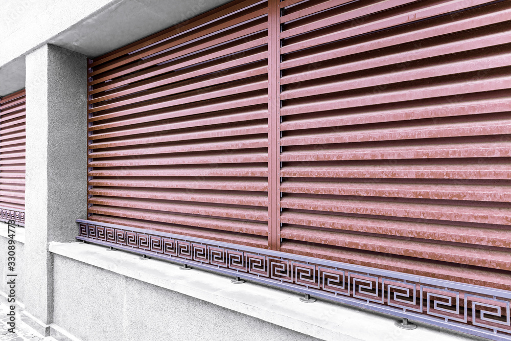 Fototapeta premium facade of modern building with windows row, red metal protective blinds and wrought metal railings
