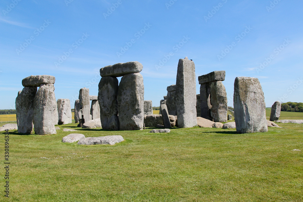 View of Stonehenge with green meadow and blue sky on a sunny day in Spring, United Kingdom