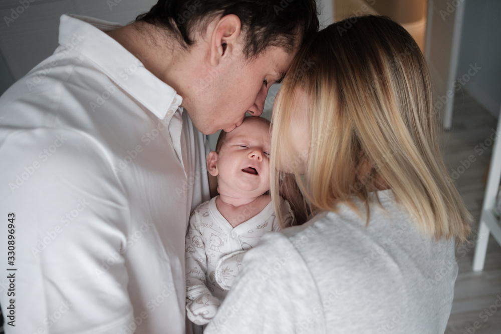 Woman and man holding a newborn. Mom, dad and baby. Close-up. Portrait of young smiling family with newborn on the hands. Happy family on a background.