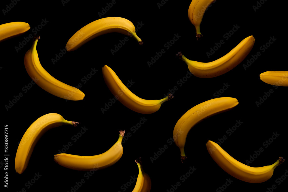 A lot of falling bananas on a black background. Ripe yellow bananas. 