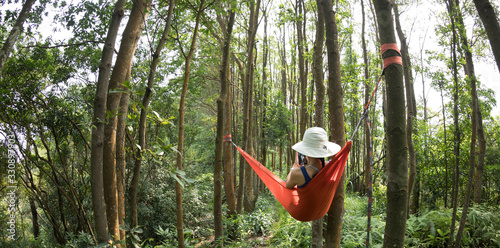 Woman relaxing in hammock using smartphone in rainforest