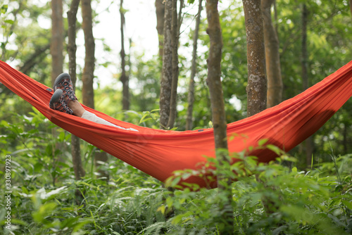 Woman hiker relaxing in hammock in rainforest