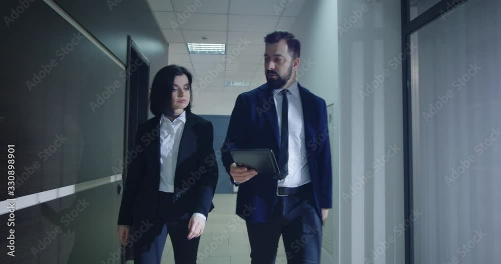 Manager explaining to coworker while walking Manager explaining to coworker while walking