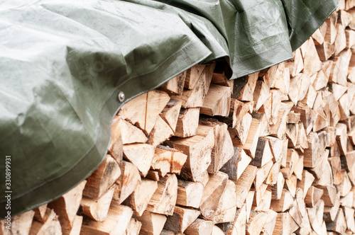 firewood covered with a waterproof green tarpaulin photo