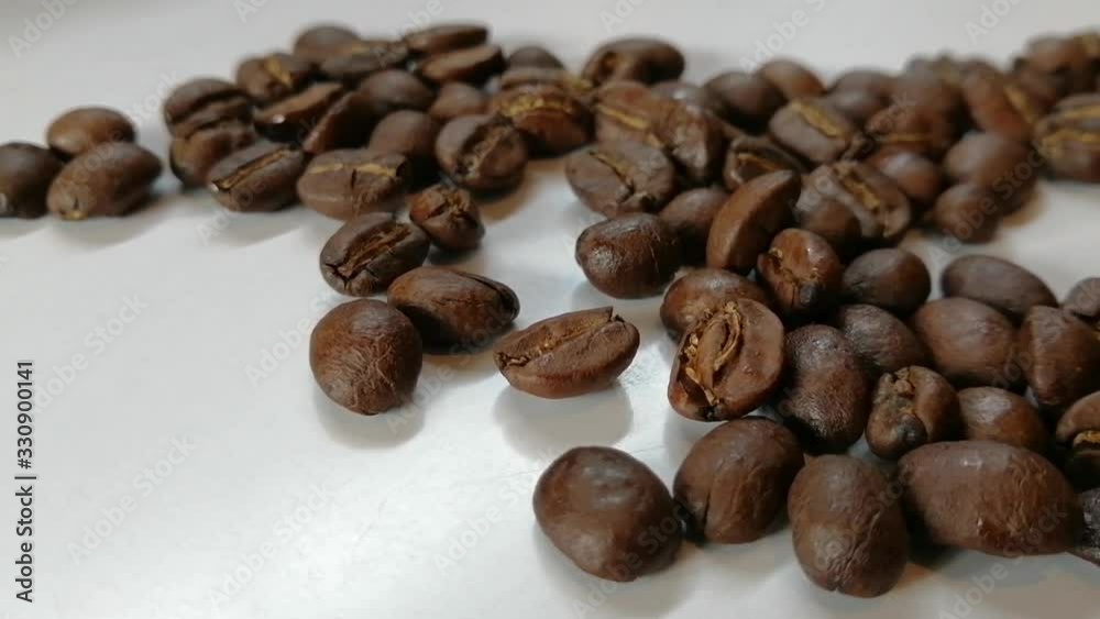Roasted coffee beans drop to coffee bean pile on white floor and shaking by wind blow. Roasted coffee beans drop to coffee bean pile on white floor and shaking by wind blow.