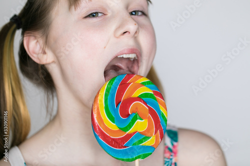 Young girl licking colorful lollipop
