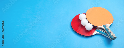 Canvas-taulu Table tennis rackets and a white plastic balls on a blue background