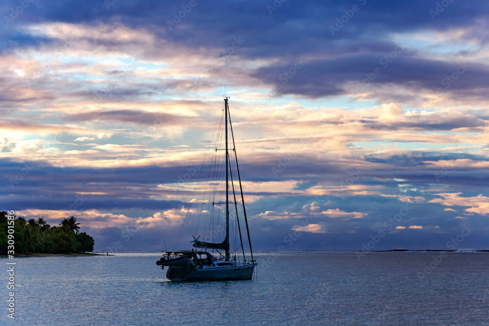 Lonely catamaran at sunset near Tahaa island in the Pacific ocean, French Polynesia.