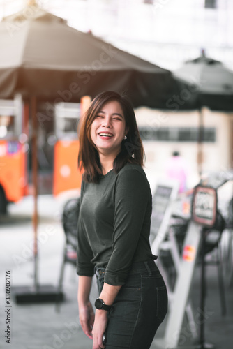Portrait of Smart Asian Woman Smiling in Front of Coffee Shop at Co-Working Space in Shopping Center on Business District Location - Happy Emotion Relax Concept (Vintage Film Tone) © Platoo Studio