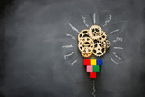 Education concept image. Creative idea and innovation. Wooden gears light bulb metaphor over blackboard