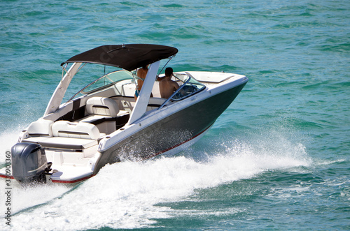 Angled view of a motor boat with black canvas canopy and one outboard engine.