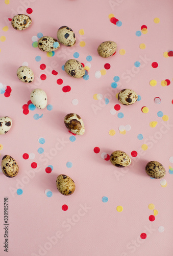 Quail eggs on a pink background with colorful confetti