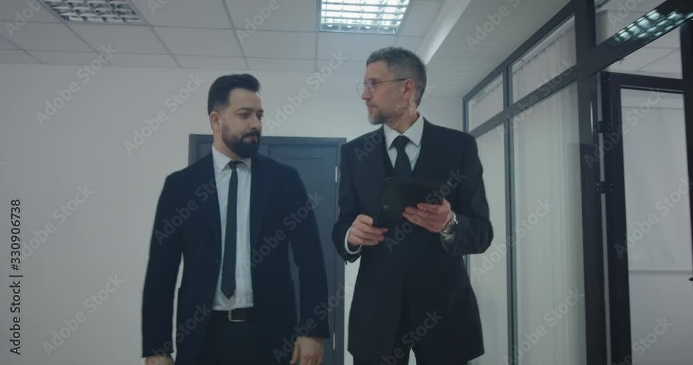 Manager explaining to coworker while walking Manager explaining to coworker while walking