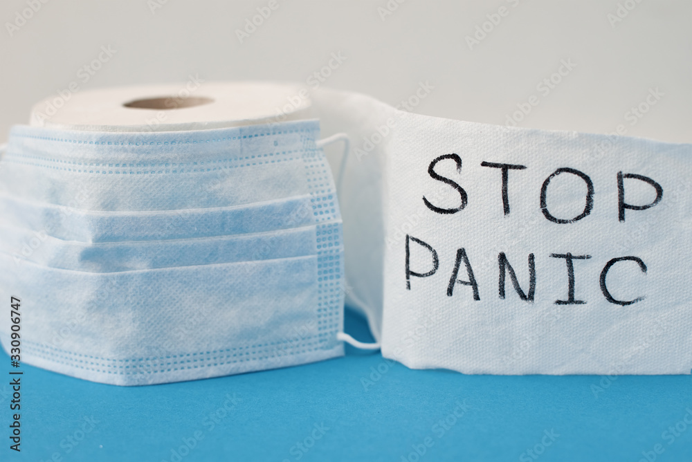 Panic buying Covid-19 Coronavirus outbreak concept. Roll of toilet paper with inscription stop panic and surgical mask on the blue background. - obrazy, fototapety, plakaty 