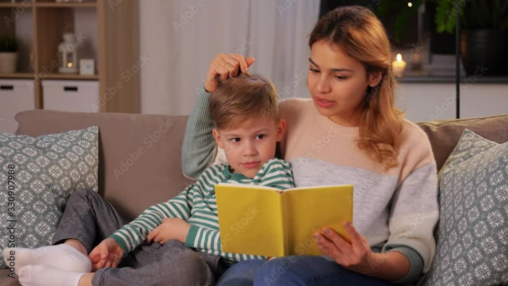 family, leisure and people concept - happy smiling mother and little son reading book on sofa at home family, leisure and people concept - happy smiling mother and little son reading book on sofa at home