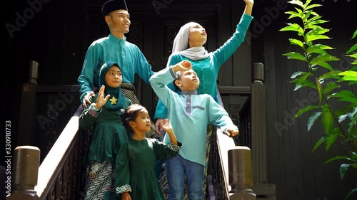 malay family standing at front yard waving said goodbye