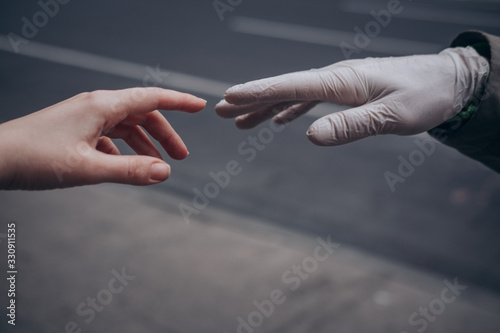 Bare hand reaching towards gloved hand photo