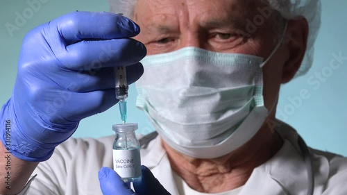 Old doctor holding Coronavirus vaccine, nurse with blue gloves prepares Sars-CoV-2 medical remedy in syringe, aged scientist getting ready medicine treatment against COVID-19, 2019-nCoV vaccination 