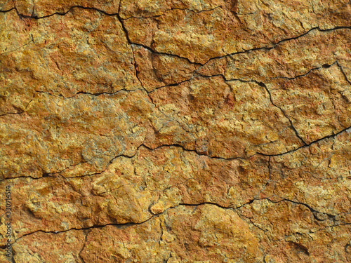 Red grunge background. Rock texture with cracks. Red brown yellow mountain texture closeup. Cracked stone surface. Natural stone background.