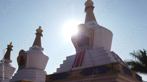 Wide angle tilt down jib shot of Buddhist prayer Stupas at the Dhondenling monastery on a bright sunny day photo