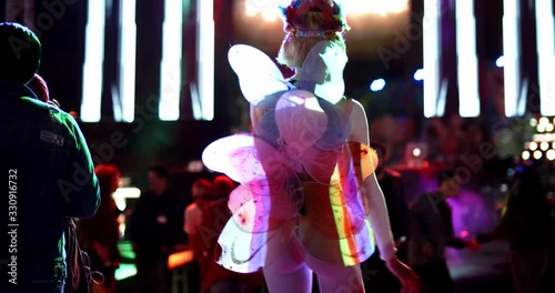 girl who has butterfly costume  is dancing at music festival