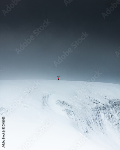 a man stands on top of a mountain with a snowboard over his head